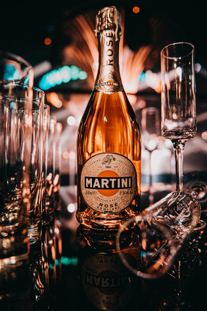 services-01 Close-up of a Martini Rose bottle with elegant champagne flutes on a reflective surface, perfect for celebrations.