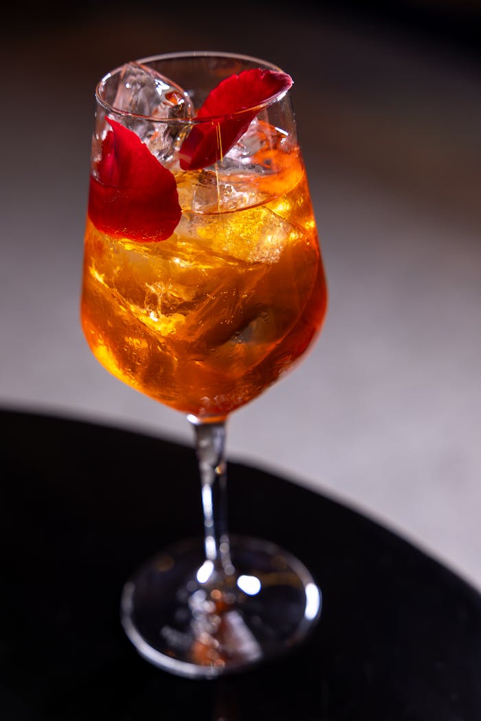 services-02 Sophisticated cocktail with ice and rose petals in stem glass, perfect for luxury occasions.